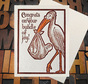 Letterpress Card with an image of a stork carrying an upset baby in a sack with the text, "Congrats on your bundle of joy!"