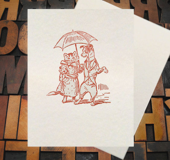 Letterpress Card with an image of a dog and cat holding an umbrella while wearing clothes