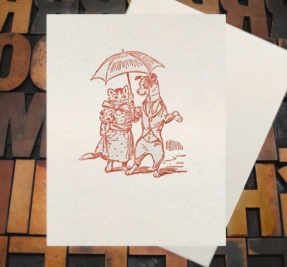 Letterpress Card with an image of a dog and cat holding an umbrella while wearing clothes
