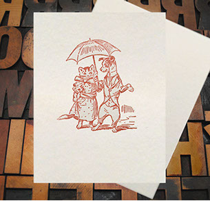 Letterpress Card with an image of a dog and cat holding an umbrella while wearing clothes